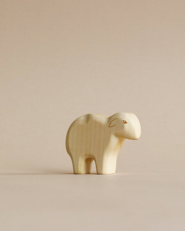 A Handmade Holzwald Sheep figurine, featuring simple, smooth contours and natural wood grain, standing against a plain, light beige background. This piece is ideal among sustainable toys for eco-conscious collectors.