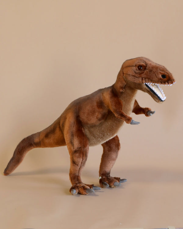 A T-Rex Stuffed Animal standing against a plain beige background, featuring detailed stitching and a realistic design with sharp white teeth and focused eyes. This artisan hand-sewn figure captures the