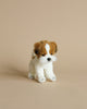 A small, realistic Jack Russel Tea Cup Dog Stuffed Animal with brown, white, and black fur, looking to the side, against a plain light tan background.