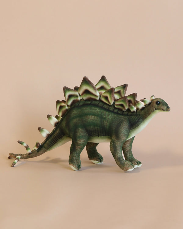 A realistic Stegosaurus Stuffed Animal with detailed skin and plate textures, painted in shades of green and brown, standing against a plain light beige background.
