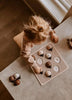 A young child plays with the My Little Lady Bug Wooden Puzzle on a table near a window, reaching to place a ladybug-shaped piece into the board.