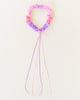 A Sarah's Silk Blossom Garland Headband is pink and purple with long dangling ribbons, reminiscent of festive garlands. The headband is ruched and the ribbons extend from the bottom, adding a decorative touch. Perfect for dress-up play, it is set against a plain, light background.