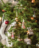 A Christmas tree adorned with animal-shaped ornaments, including the Coral & Tusk Fox Tree Trimmer Ornament, owl, and elephant, along with round baubles and glowing lights—a festive holiday gift with a cozy, softly blurred background.