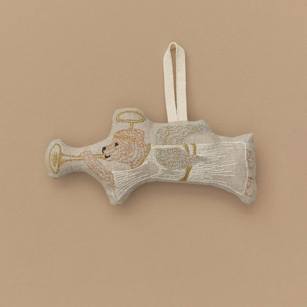 A decorative fabric ornament shaped like an angel dog with wings and a halo, playing a gold horn. It features a looped ribbon for hanging, perfect for bringing festive charm to your home against a plain tan background this Christmas.