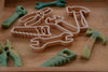 The Tools Cutter Set - Eco Playdough Tool, featuring plastic cookie cutters shaped like a wrench, pliers, saw, and hammer, is arranged on a wooden surface alongside Eco Playdough tools.