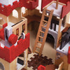 A close-up of the Lionheart Wooden Castle, beautifully crafted from sustainable wood and featuring vibrant red battlements, a working drawbridge, a ladder, banners adorned with lion emblems, as well as detailed windows and a dungeon gate. This colorful structure is designed to spark imaginative play.