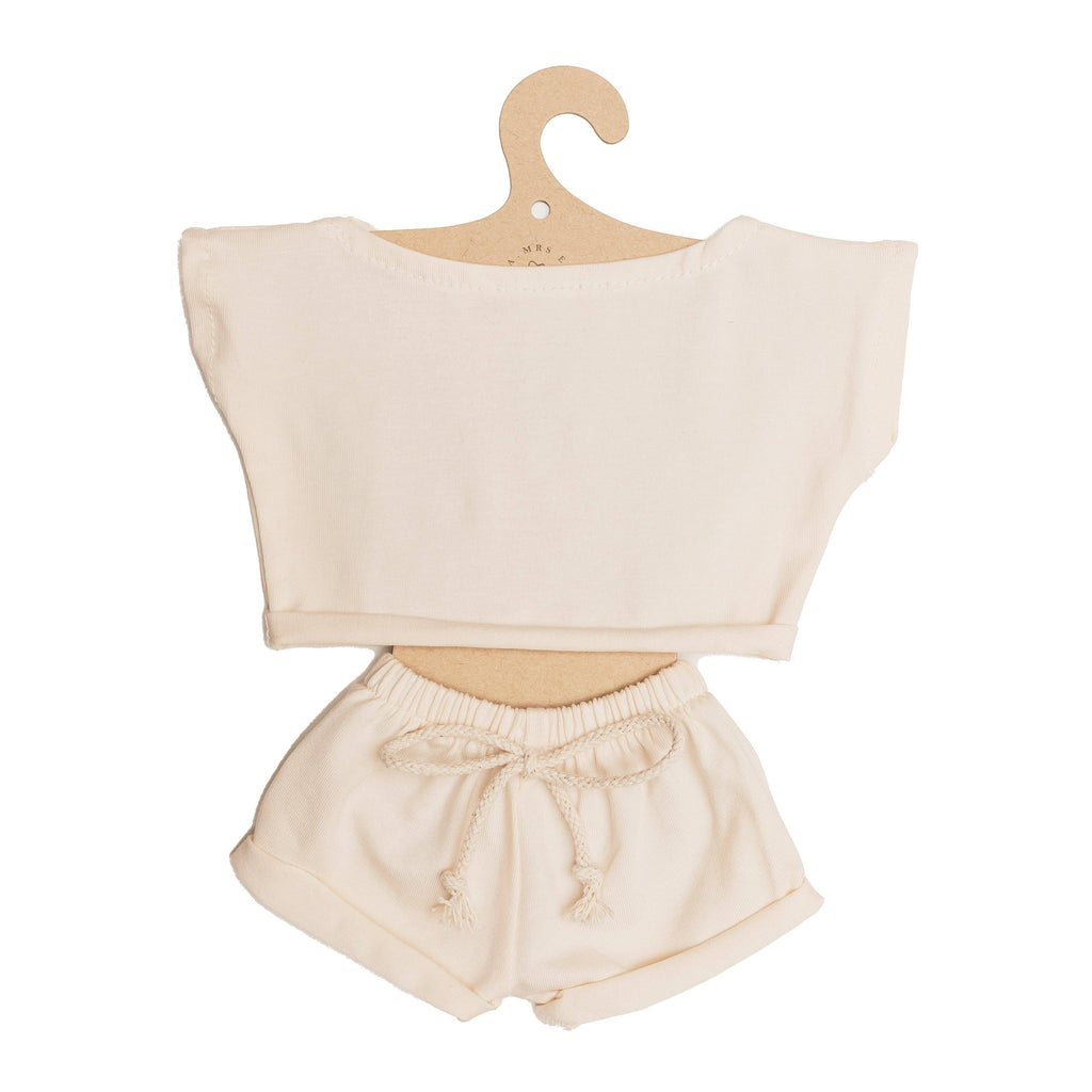 Introducing the Mrs. Ertha Doll Clothes - 13″-14″ - Ivory Comfy Set: a cream-colored, handmade outfit for Minikane doll clothes collections featuring a short-sleeve top and drawstring shorts, beautifully presented on a hook-shaped cardboard hanger.