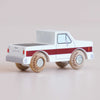 The No. 30 GT165 Charlie | Made in England is a classic toy truck crafted from white wood, accented with a bold red stripe and sturdy wooden wheels. Displayed from the back left side, it features “Le Toy Van” printed on both the wheels and tailgate, making this charming off-road vehicle perfect for imaginative play.