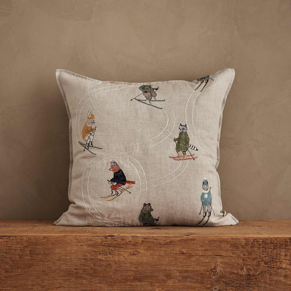 The Coral & Tusk Downhill Skiers Pillow features embroidered animals skiing on winding trails, creating a whimsical alpine scene on a beige background—an elegant accent for any room.