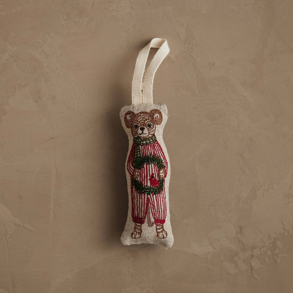 The Coral & Tusk Mouse with Wreath Ornament, wearing festive attire and featuring a loop for easy hanging, rests on a textured beige surface—an adorable addition to any holiday wreath.