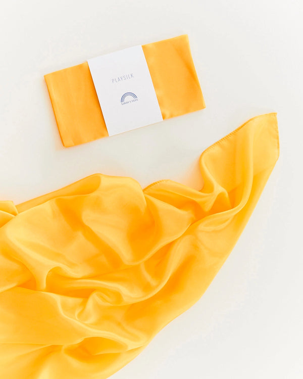 A vibrant yellow silk scarf elegantly displayed next to its packaging labeled "Sarah's Silk Playsilk - Gold" on a white background.