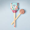 The Pollinator Seed Pop (Single) features wildflower seeds in a vibrant floral package with a "Plant Me!" stick and soil disc—perfect for starting a pollinator garden, all displayed on a light blue background.