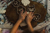 A child presses their hands onto the Pet Friends Faces Cutter Set – Eco Playdough Tool, shaping dough on a wooden board and transforming sensory play into a delightful activity. The scene is arranged atop patterned fabric.