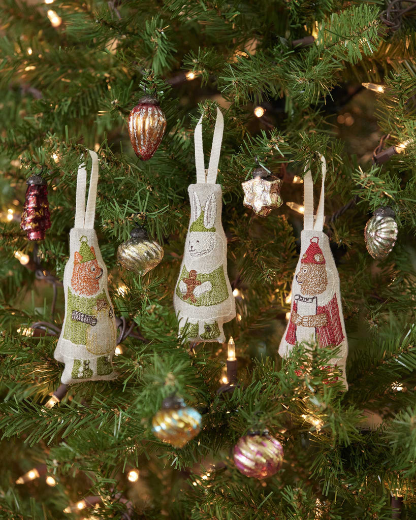 A Christmas tree adorned with twinkling lights and shiny North Pole Bear Ornaments, featuring embroidered animal decorations, including a Santa Bear, rabbit, and fox.