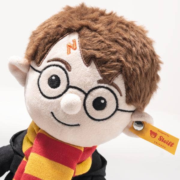 The Steiff Harry Potter Plush 11" features round glasses, brown hair, a lightning scar, and a red and yellow scarf with a black robe. A yellow Steiff tag on its ear makes it the ideal collectible Hogwarts stuffed toy.