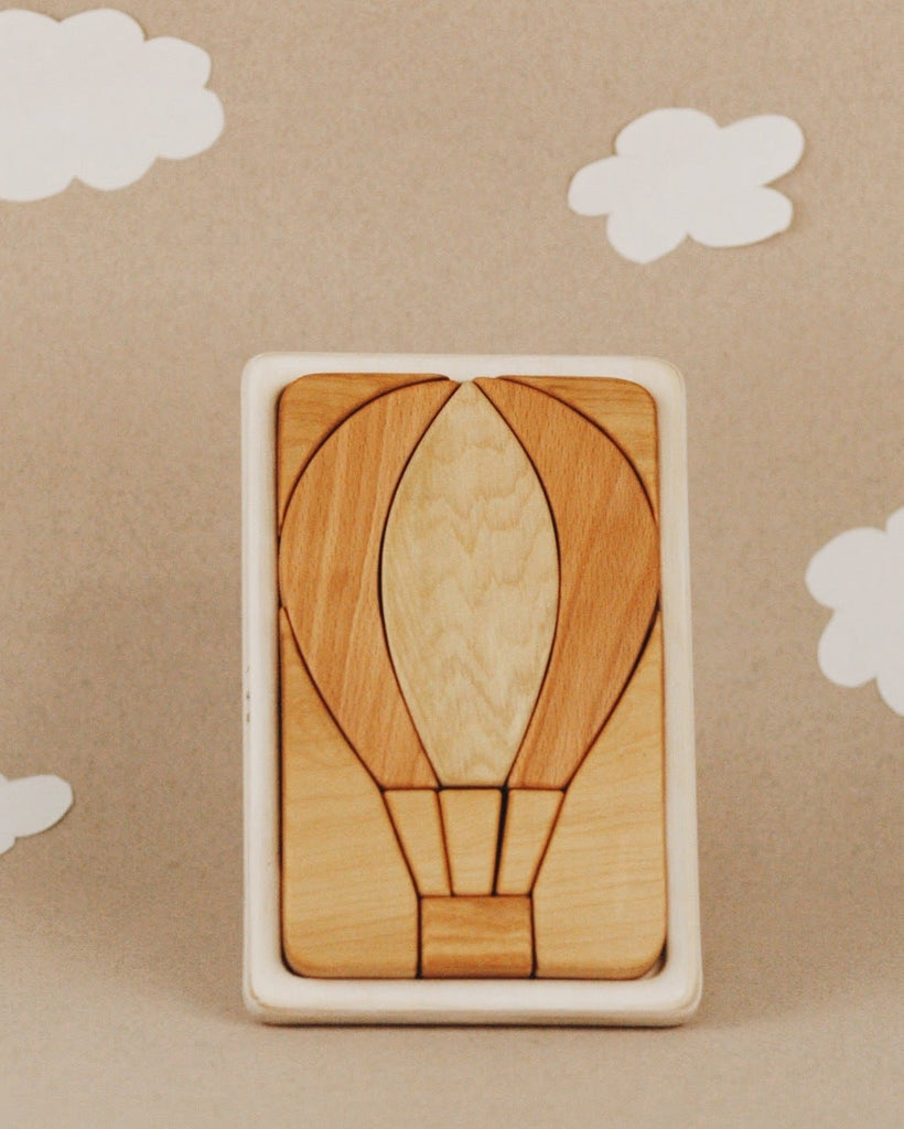 The Handmade Hot Air Balloon Puzzle is a wooden puzzle enhanced with linseed oil for a rich finish, featuring a design of a hot air balloon against a beige background with white paper clouds.