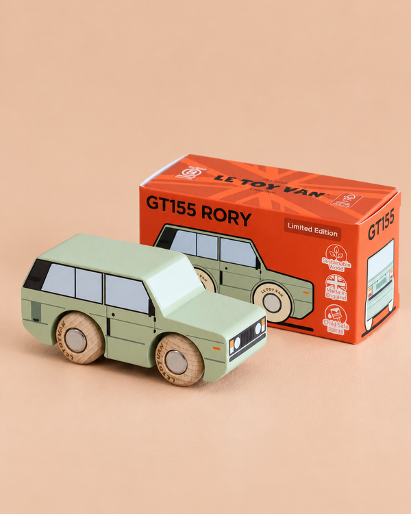 A green wooden toy car, inspired by classic British design, is displayed in front of an orange box labeled “No. 28 GT155 Rory | Made in England,” featuring illustrations and product details. The background is a light beige surface, inviting imaginative play for children and collectors alike.