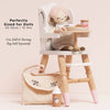 The Dolls Wooden High Chair features pink-tipped legs and fits dolls 30-35cm (12-14in). Includes a small bottle, cup, and cream-colored cloth bag. Eco-friendly. Cot, Doll & Nursing Bag sold separately.