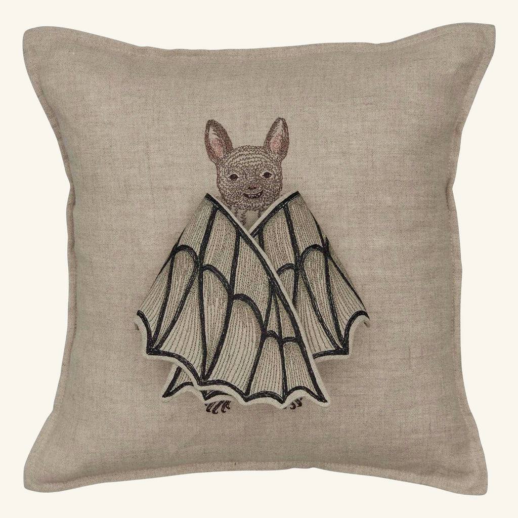 The Coral & Tusk Bat Wing Surprise Pillow is a beige throw pillow embroidered with a smiling bat wrapping its wings around itself, adding cozy bat plush charm to your space.