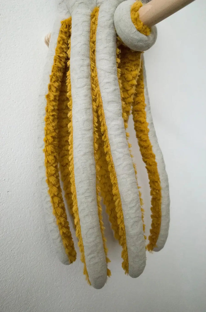 A close-up shot of an octopus soft toy draped over a wooden rod. The BigStuffed Octopus - Pop features eight long, fluffy tentacles with white bases, set against a plain white background.