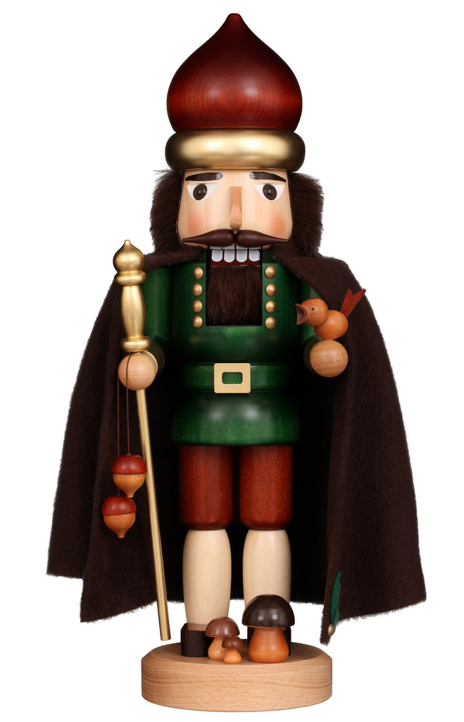 The Christian Ulbricht Collectible Wooden Nutcracker - Forest King, made in Germany, features a green coat, brown cape, staff and bird in hand, mushrooms at its feet, a large round hat, and a painted bearded face.