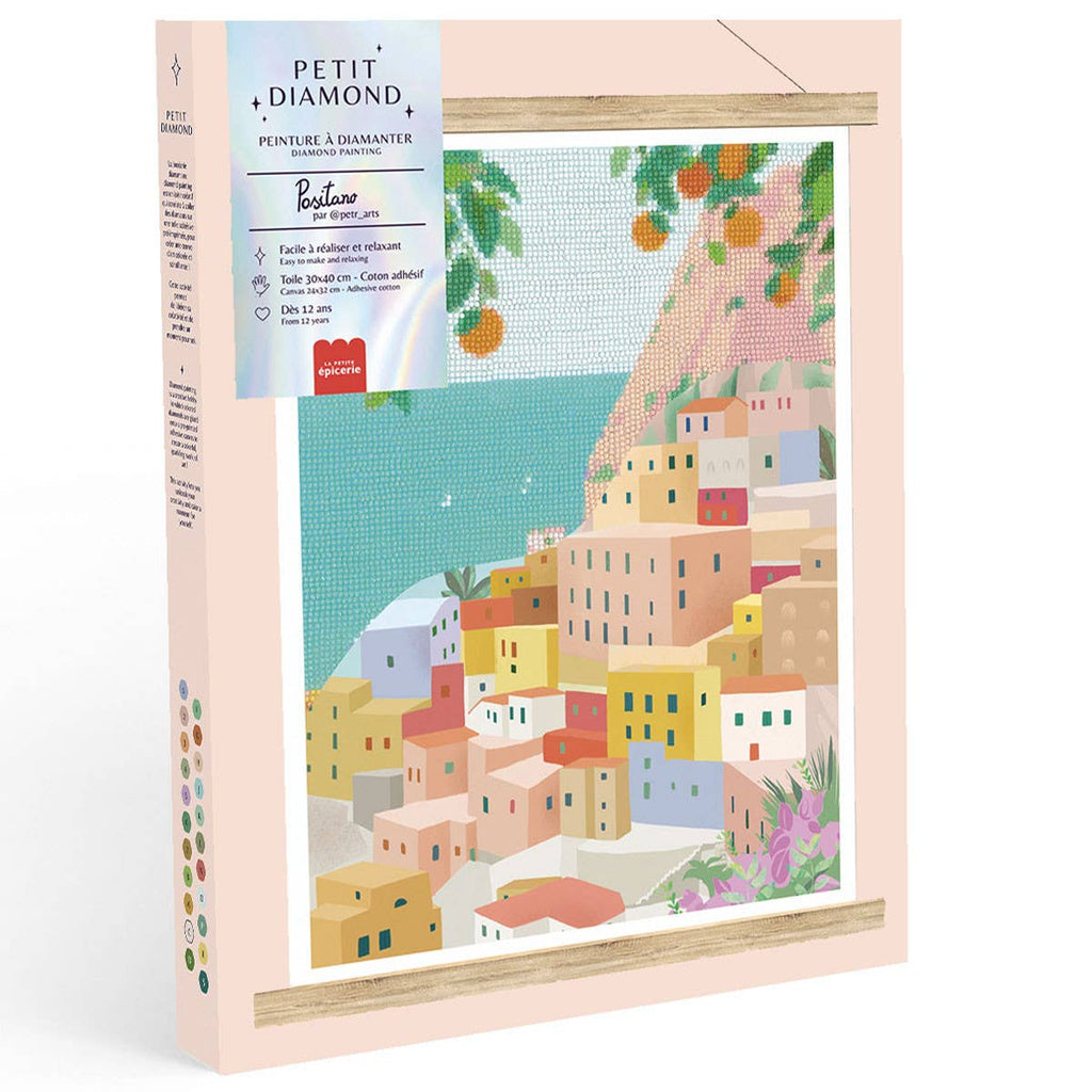 The Diamond Painting Kit - Positano by Petra Lidze features colorful Mediterranean-style houses on a seaside hillside, orange trees overhead, and a pastel pink border on the box.