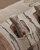 A close-up of the Coral & Tusk Aspen Log Bunnies Pocket Pillow shows embroidered bunnies peeking through a cut-out window, surrounded by detailed stitching, textured patterns, and neutral-toned linen fabric.