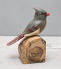 The Hand Carved Ornament - Cardinal Bird- Female - 7"H features a handmade, gray, red, and cream-painted wooden bird on an unfinished wood block—an elegant anniversary gift against a light gray background.