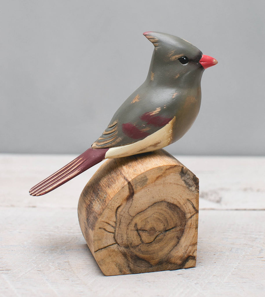 The Hand Carved Ornament - Cardinal Bird- Female - 7"H features a handmade, gray, red, and cream-painted wooden bird on an unfinished wood block—an elegant anniversary gift against a light gray background.
