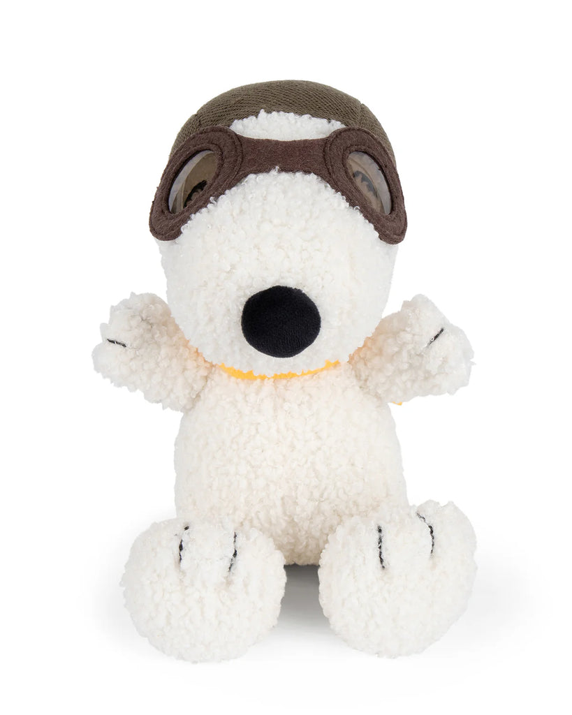 The Plush Peanuts Snoopy Sitting Flying Ace by Bon Ton Toys features soft, white textured fabric, brown aviator goggles, a green cap, black nose, and black stitching on its paws. Inspired by the Peanuts comic strip.