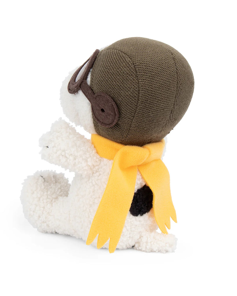 A Plush Peanuts Snoopy Sitting Flying Ace from Bon Ton Toys faces left on a plain white background, wearing a brown aviator hat, goggles, and a yellow bow-shaped scarf—mirroring his iconic look from the classic Peanuts comic strip.