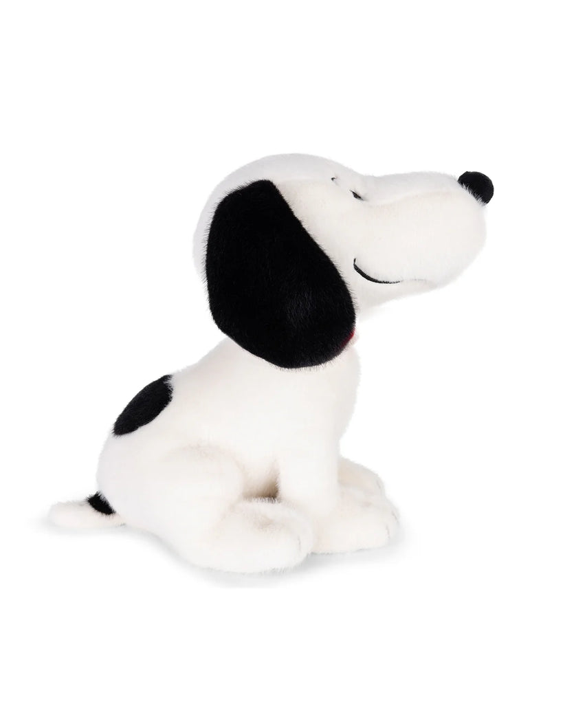 The Plush Peanuts Snoopy Good Ol' Charlie Brown from Bon Ton Toys is a white plush toy dog with big black ears and spots, sitting upright and smiling with closed eyes against a plain white background.