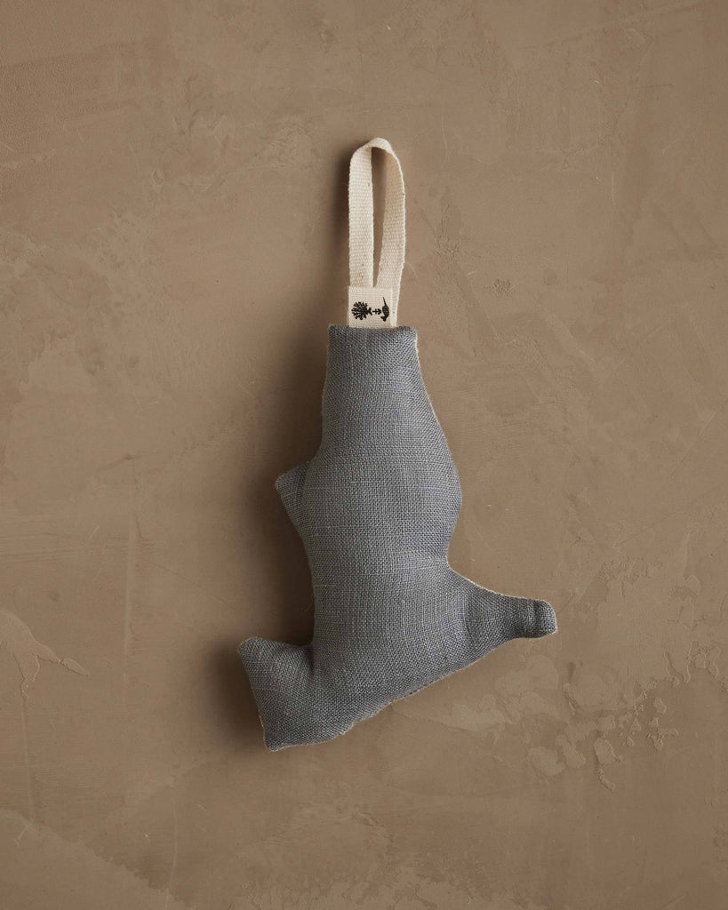 The Coral & Tusk Downhill Bear Ornament is a small, abstract-shaped fabric decoration in muted gray with a cream loop for hanging, adding winter charm to any beige textured wall.