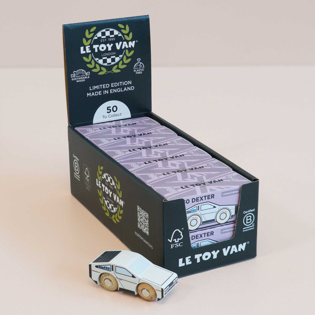 A display box labeled “Le Toy Van” presents several boxed toy cars, with a No. 23 GT130 Dexter—a small, white modern toy car featuring wooden wheels—placed in front. The box highlights “Limited Edition,” “Made in England,” and notes there are “50 to collect.” Perfect for inspiring imaginative play, the futuristic wooden No. 23 GT130 Dexter is a delightful addition to any collection and is available for pre-order for August 2026.