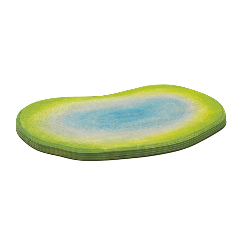 A small, irregularly shaped Ostheimer Pond with gradient colors resembling a pond. The center is light blue, outlined with a creamy white edge, transitioning to a green border. Perfect for imaginative play with Ostheimer wooden toys, the mat has a smooth surface and appears to be made of thin, layered material.