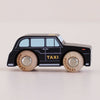 The No. 45 GT275 Bertie, made in England, is a black wooden taxi toy featuring “TAXI” on the side, light blue windows, and round wooden wheels—evoking the charm of a classic London car against a plain light background.
