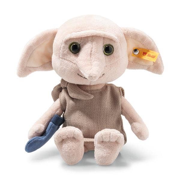 The Steiff Harry Potter “Dobby” with Sock 10" plush features large ears, green eyes, a beige tunic, holds a blue sock in its left hand, and has a yellow Steiff tag on its right ear.