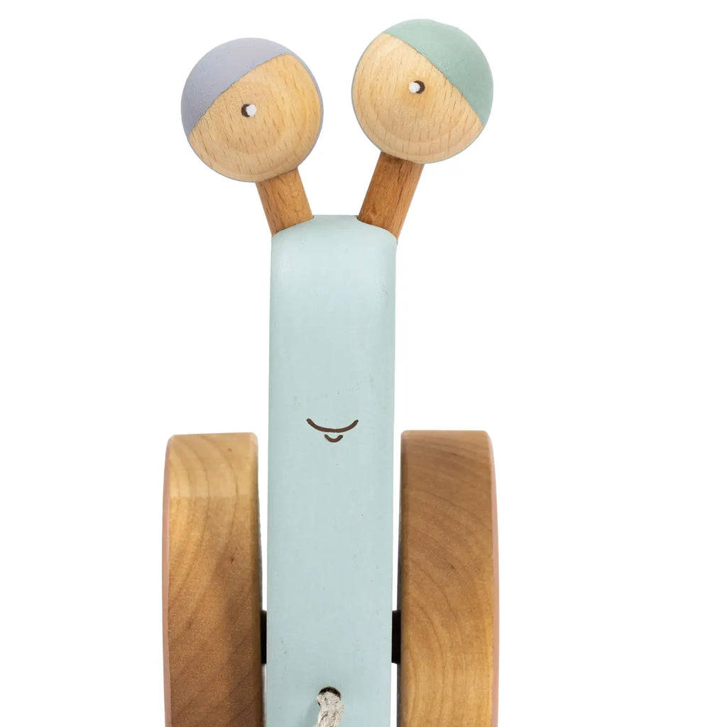 A whimsical wooden kitchen timer designed to look like a Handmade Pull Along Snail Toy, with a smiling face on a pale blue cylindrical body and two round, natural materials-topped knobs as eyes.