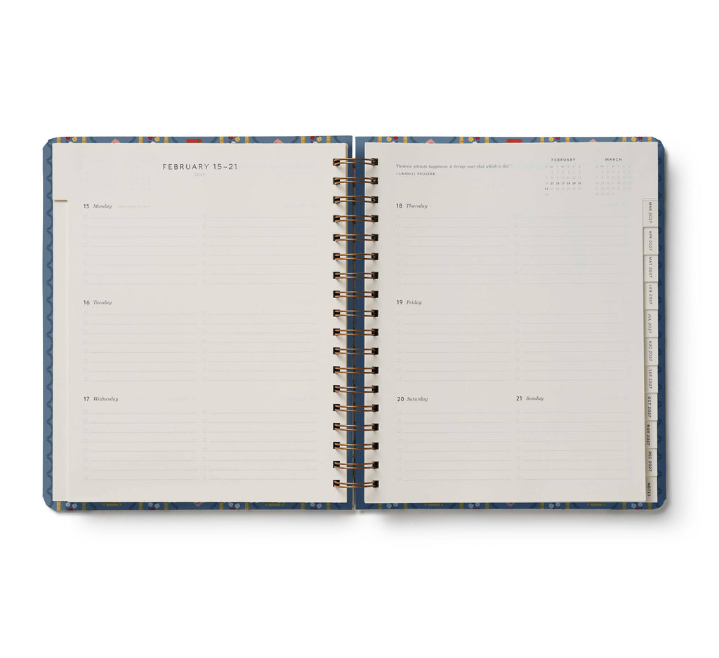 The 2027 Schoolhouse 17-Month Academic Hardcover Spiral Planner is open to a weekly layout for February 15–21, featuring lined sections for each day and monthly tabs visible along the right edge, illustrating its organized weekly and monthly planner format.