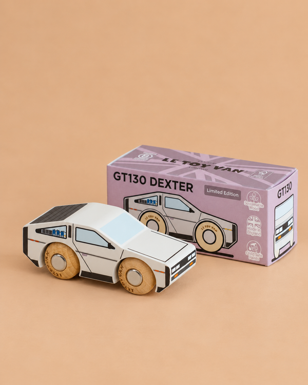 A small, modern wooden car—No. 23 GT130 Dexter | Made in England—sits beside its purple box on a beige surface, perfect for imaginative play.