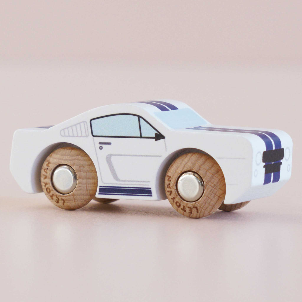 The No. 17 GT95 Maverick, a white wooden muscle car toy featuring blue racing stripes and natural wood wheels, is displayed against a plain light pink background.