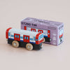 A wooden toy train painted red, white, and blue stands in front of a matching purple box labeled “No. 48 GT290 Tim | Made in England.” Perfect for imaginative play, the box features an illustration of the train and says “Limited Edition.”.