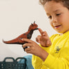 A young child in a yellow shirt holds and examines the Schleich Carnotaurus Large Realistic Dinosaur Toy With Movable Jaw, using one finger to touch its mouth.