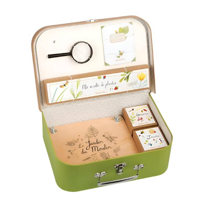 The Moulin Roty Botanist Suitcase is a green case for young botanists, labeled "Le Jardin du Moulin," featuring a magnifying glass, plant cards, envelopes, notebooks, and seed boxes—all organized for botanical adventures.