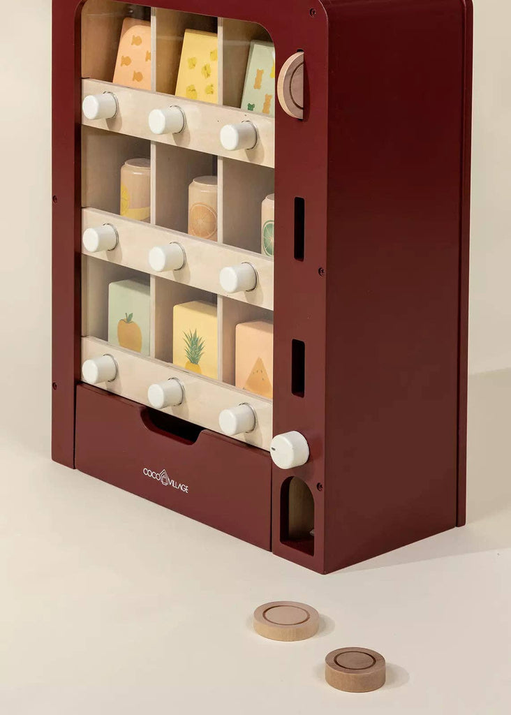 The Wooden Play Vending Machine features a maroon frame, white knobs, colorful fruit and cheese blocks, and two coin-like pieces—an ideal pretend play toy that helps children develop motor skills.