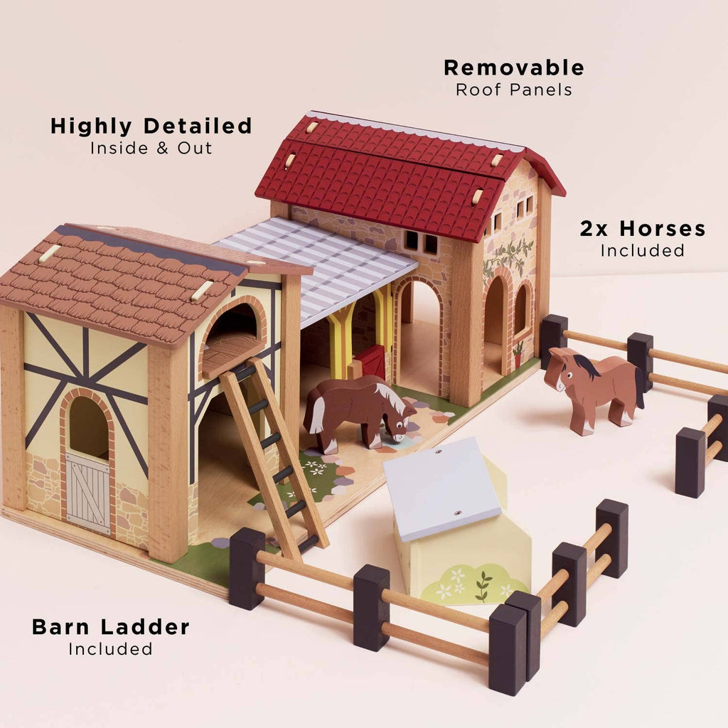 The Wooden Farmyard Stables is an FSC-certified wooden playset featuring a detailed barn with a red roof, beige and brown walls, removable roof panels, a ladder, two toy horses, a fenced area, and labeled features.
