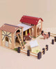 Wooden Farmyard Stables includes two stables, a fenced area, ladder, two toy horses, and a feeding station. Features red and brown barn roofs with painted details—perfect for imaginative small world play.
