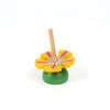 The Wooden Spinning Top - Yellow Flower features a sustainable beech wood design with a yellow flower shape, pink and blue accents, and a green base—perfect for timeless play. Set against a plain white background.