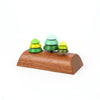 The Wooden Spinning Top Set - Tree features three pine trees in varying green shades, each crafted from stacked wooden discs on a smooth, curved base, displayed against a white background.
