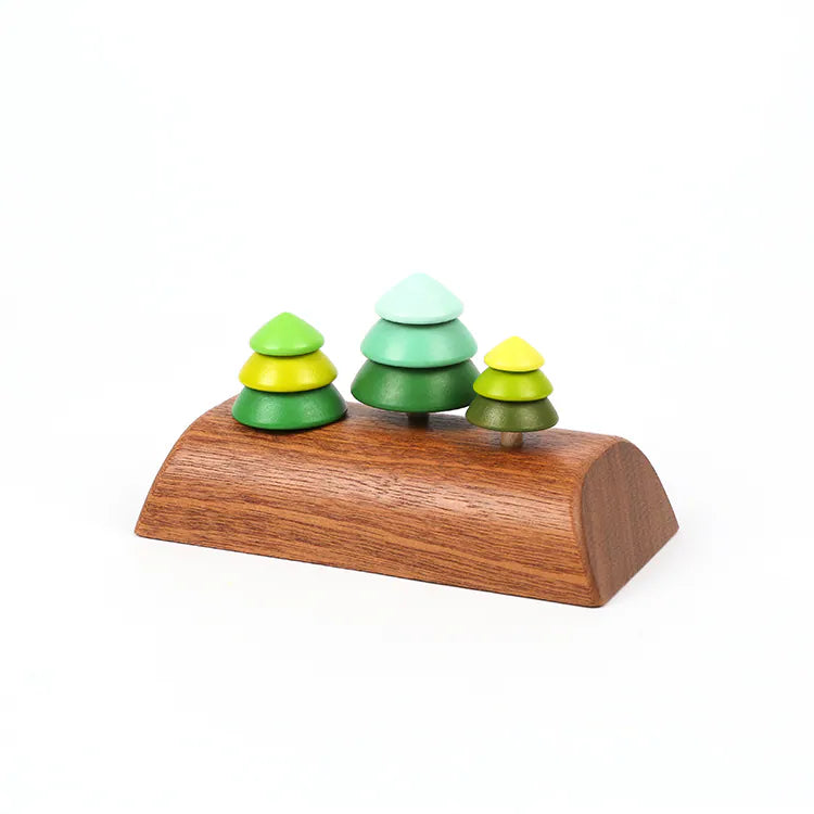 The Wooden Spinning Top Set - Tree features three pine trees in varying green shades, each crafted from stacked wooden discs on a smooth, curved base, displayed against a white background.